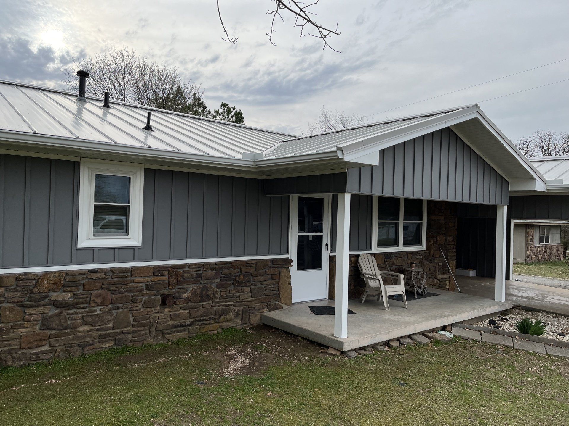 A gray house with a metal roof and a porch.