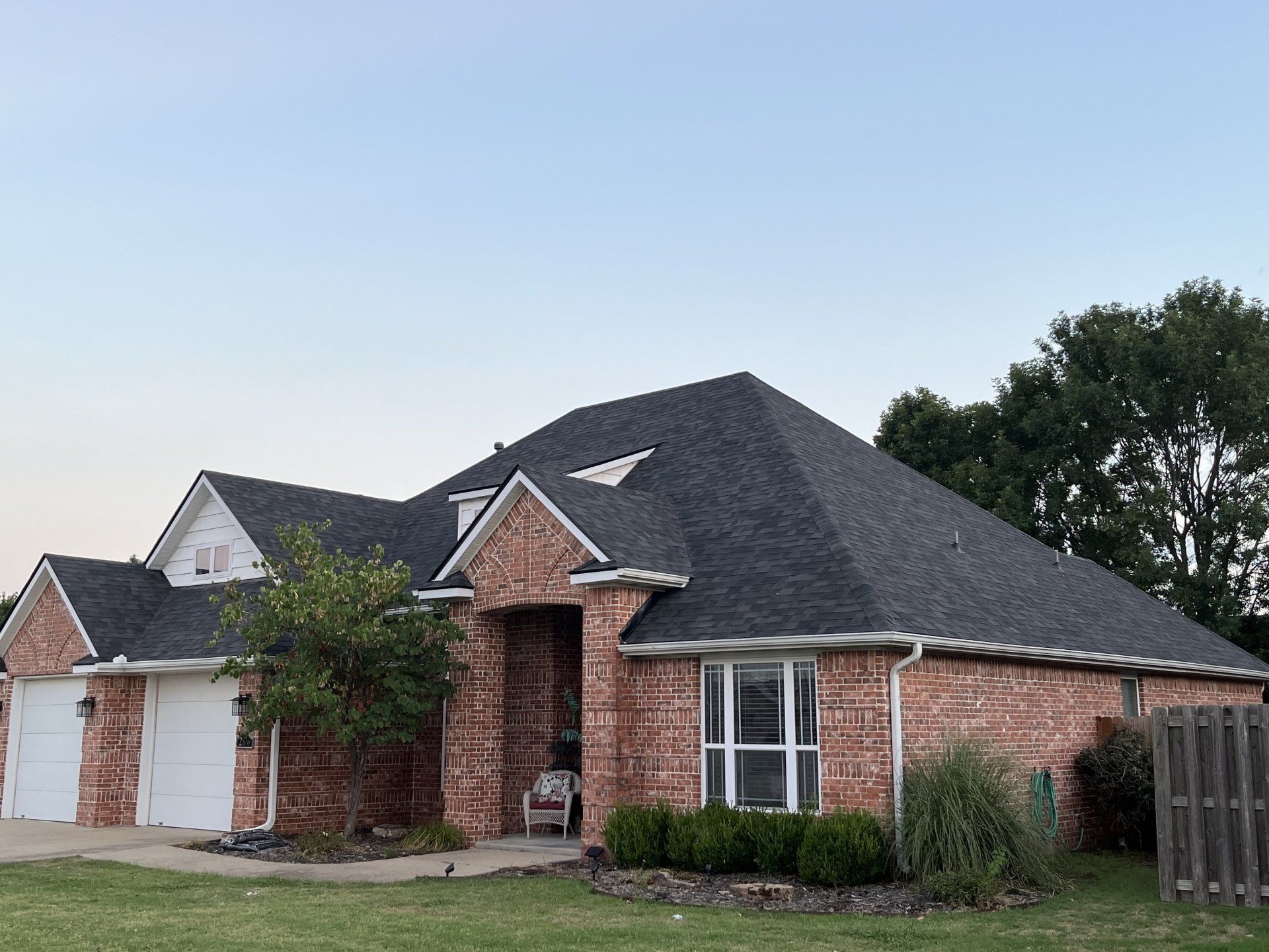 A brick house with a black roof and white trim