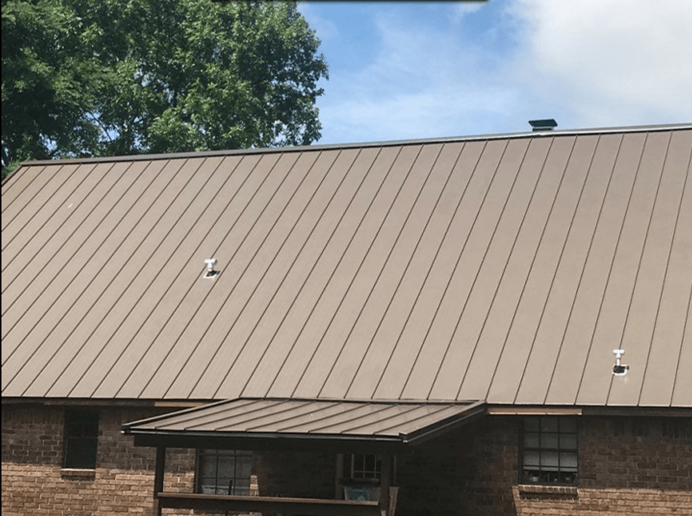 A brick house with a brown metal roof