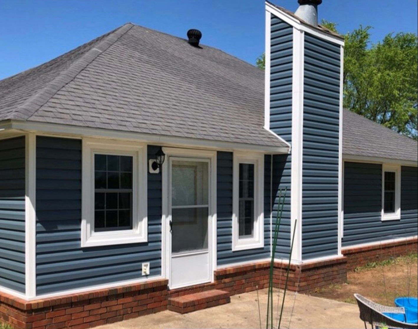 A blue house with a chimney on the side of it.