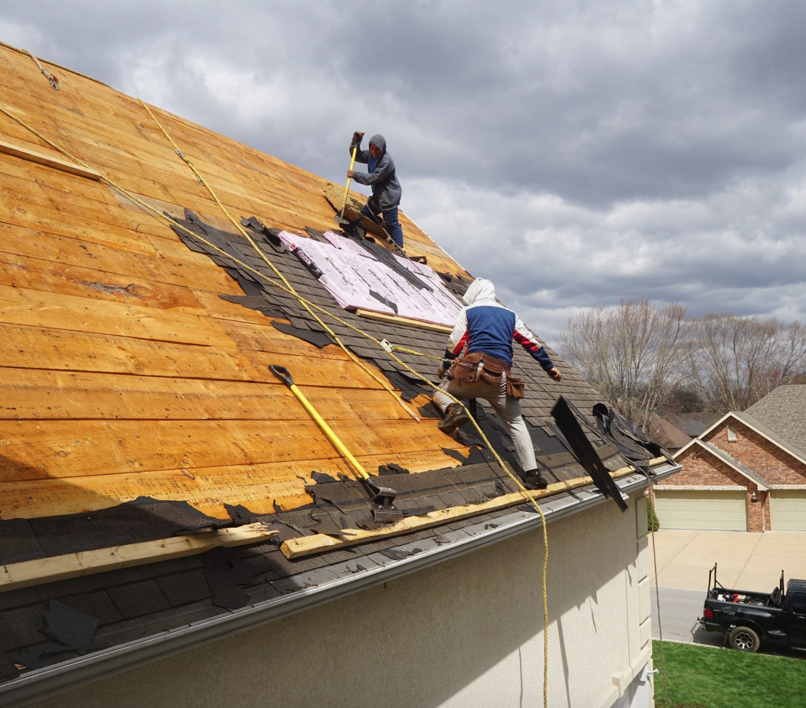 Two men are working on the roof of a house