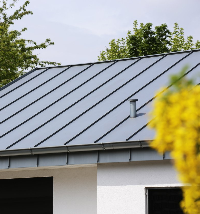 A house with a blue roof and a yellow flower in the foreground