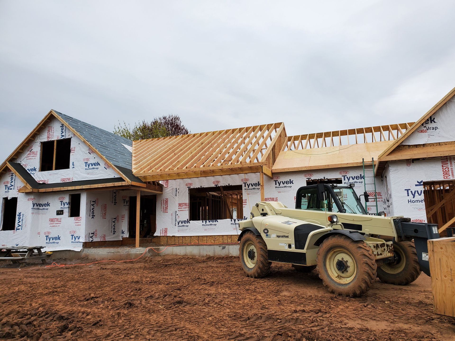 Construction site with a partially built house and a telehandler.