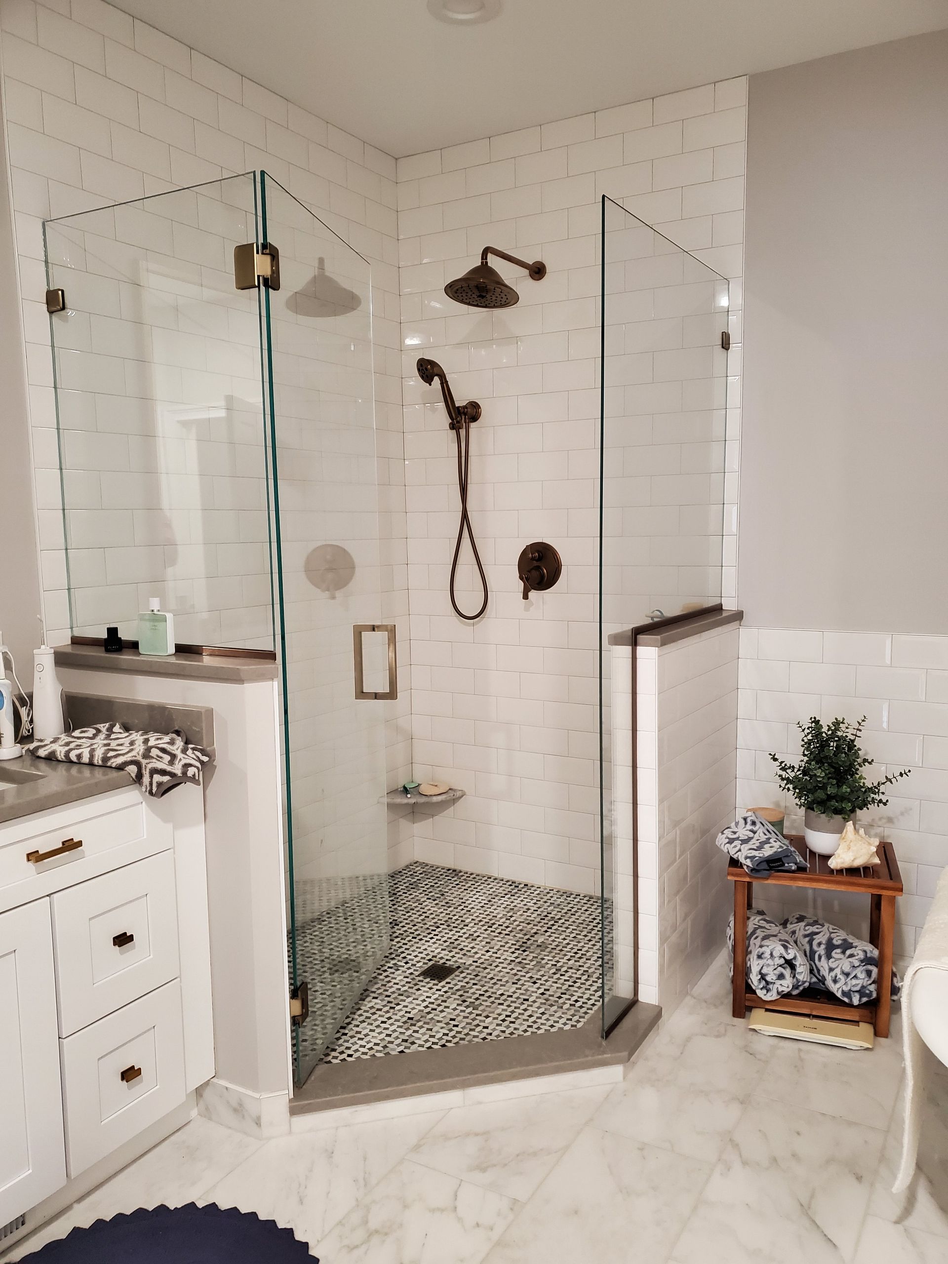 Modern bathroom with glass shower, white subway tile, and bronze fixtures.