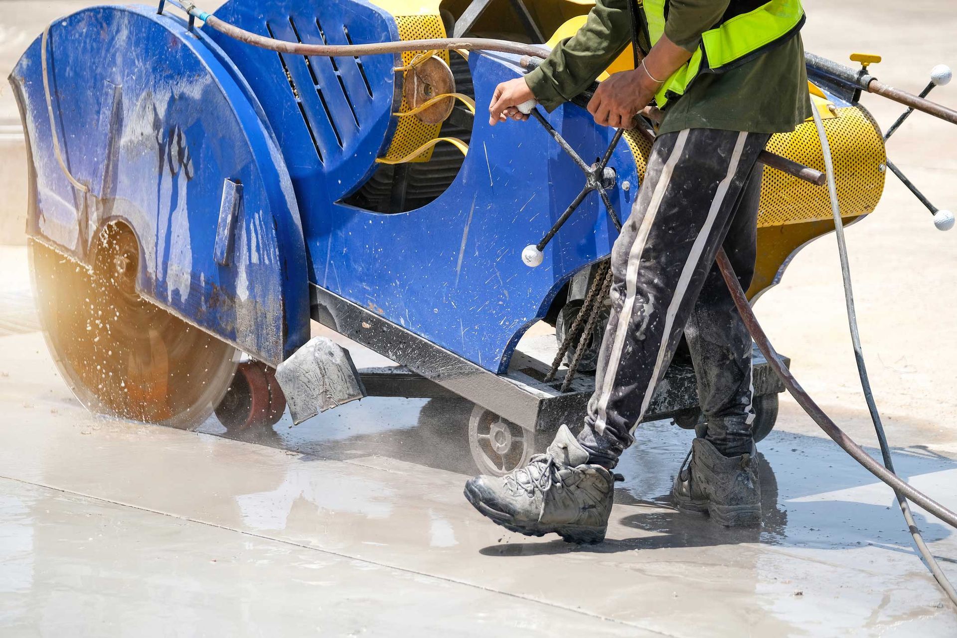 A man is using a cutting machine to cut concrete. A man is using a cutting machine to cut concrete.