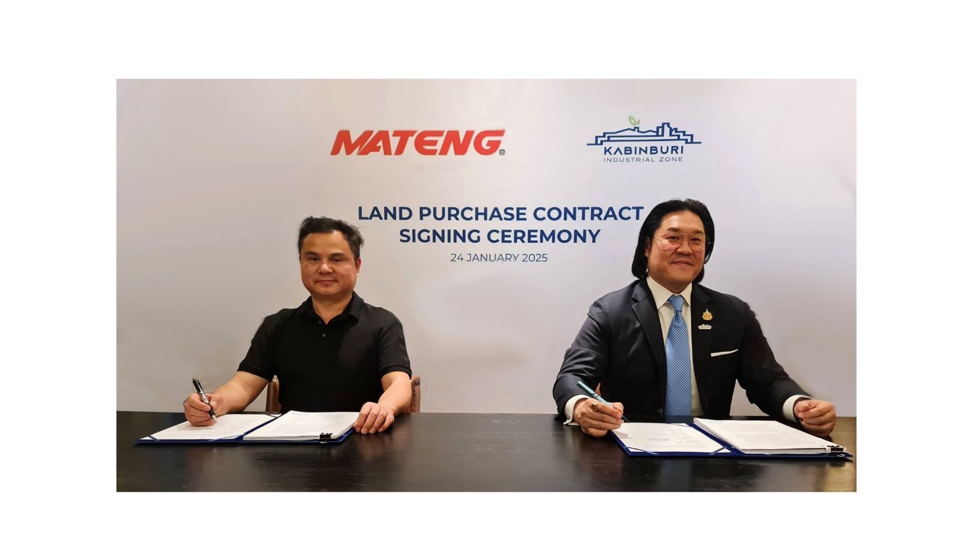 Two men are sitting at a table signing a contract.