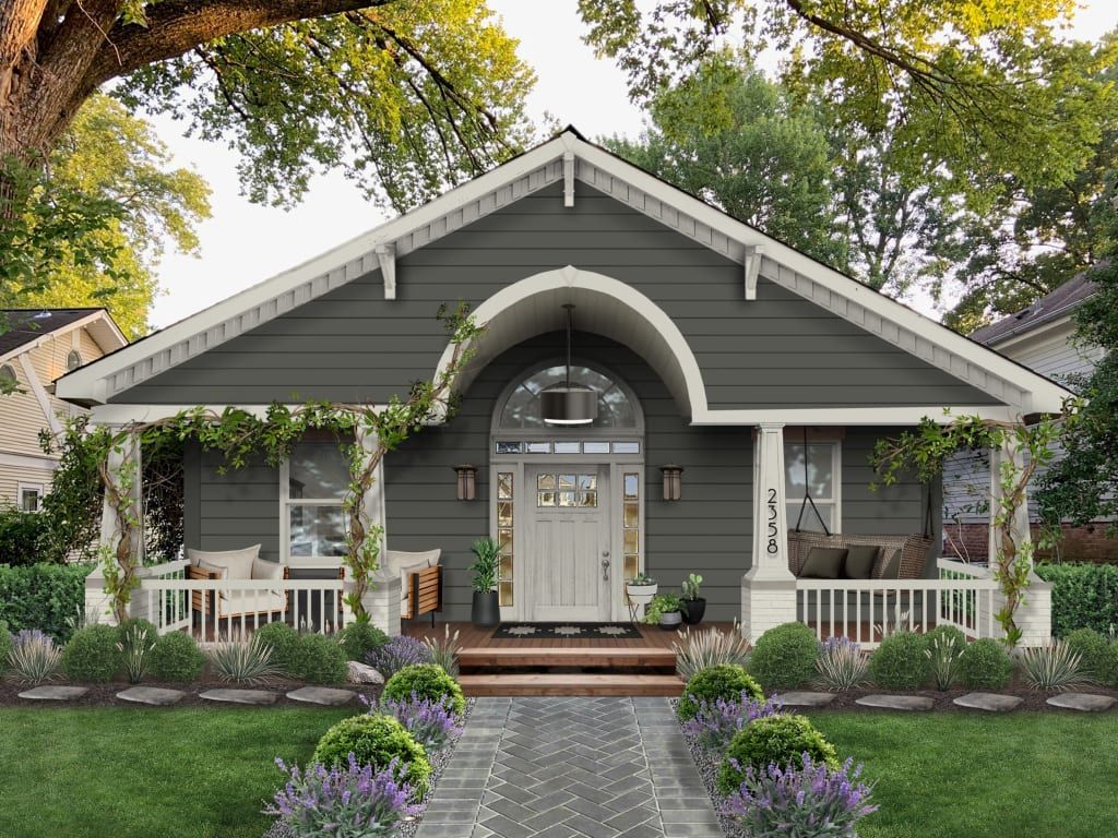 Gray cottage with arched porch, white trim, and a flower-lined front walkway
