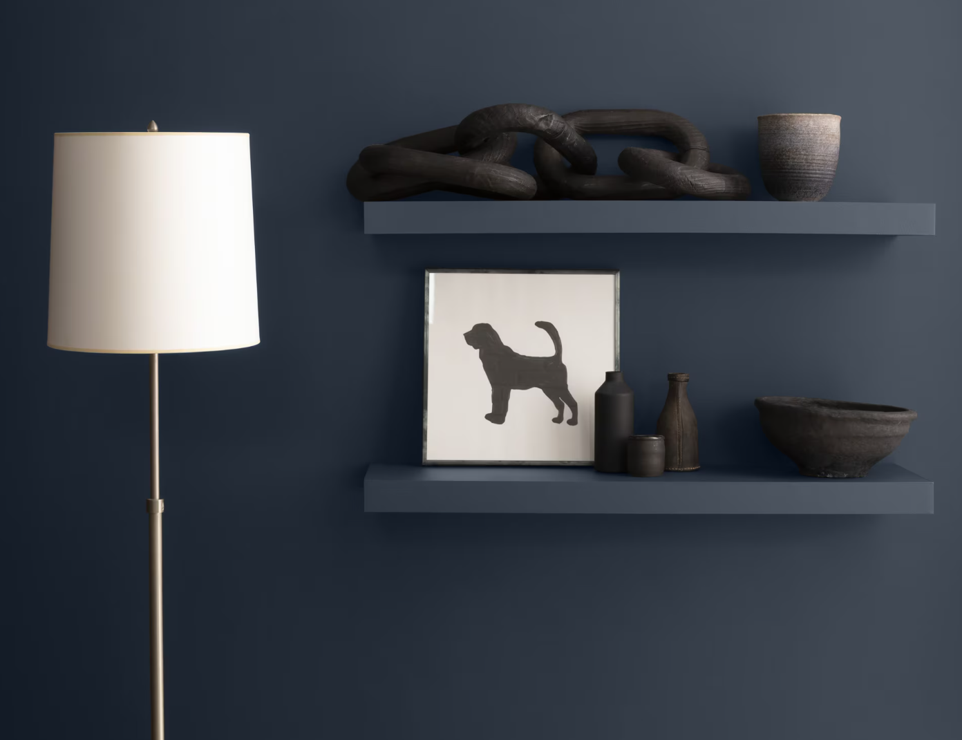 A floor lamp beside two shelves on a dark blue wall, featuring a dog silhouette print and minimalist decor objects.