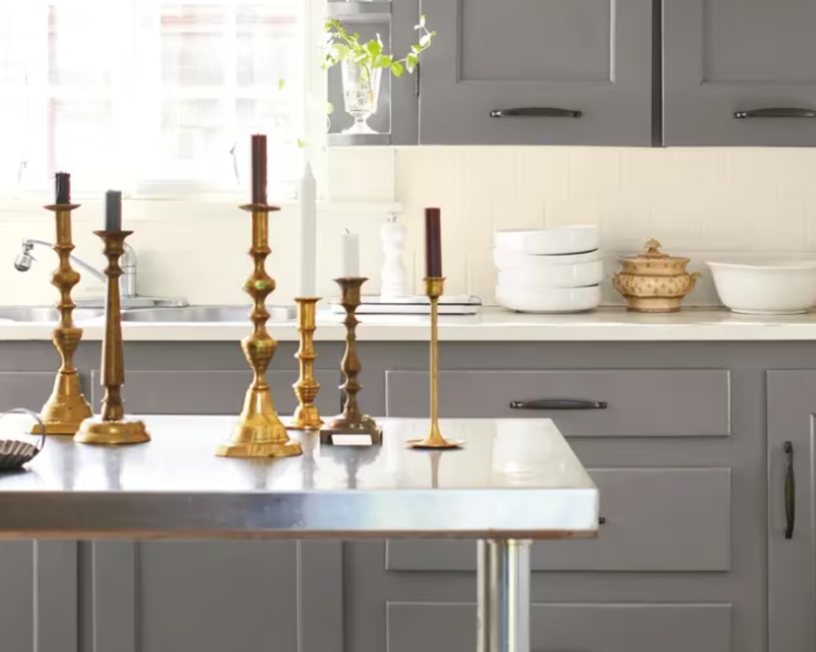Gray kitchen with brass candlesticks on a white countertop by a bright window