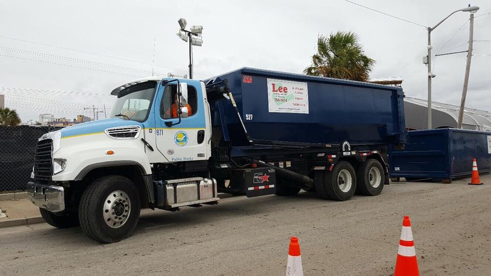 A dump truck is parked in a parking lot next to traffic cones.