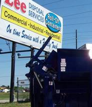 A dumpster is parked in front of a sign for disposal services.