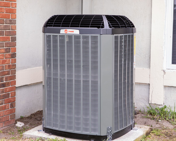 Outdoor air conditioning unit beside a building wall and window