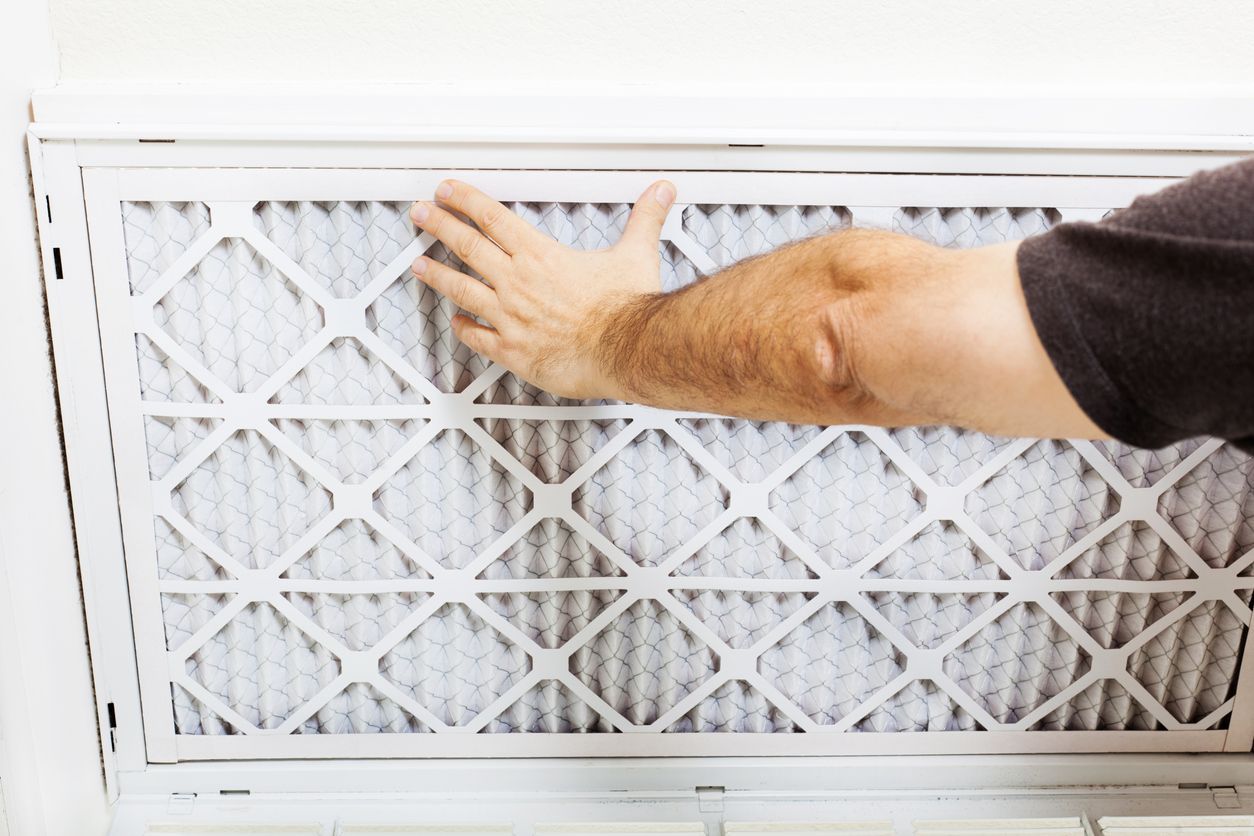 Hand pressing a dirty white air filter in a vent frame