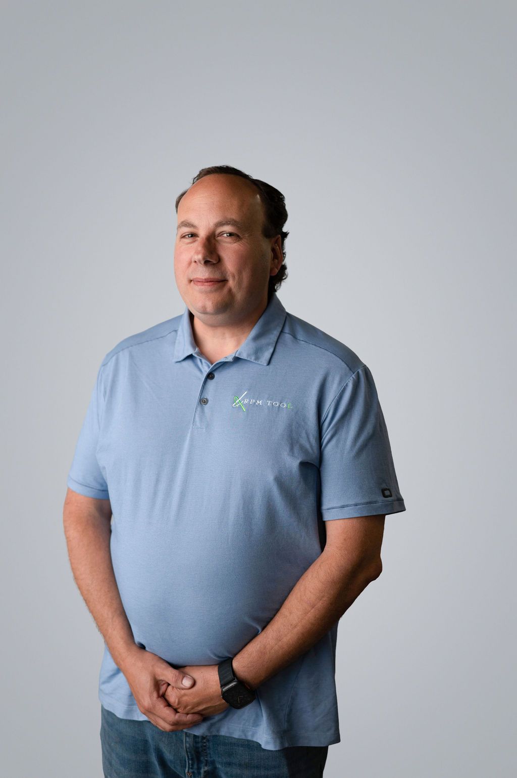 Matt Robbins in light blue polo shirt, arms crossed, standing in front of a white backdrop.
