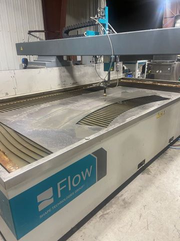 Waterjet cutting machine by Flow cutting a metal sheet in a factory setting.