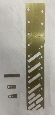 Metal strips with holes and cutouts, alongside smaller metal pieces.