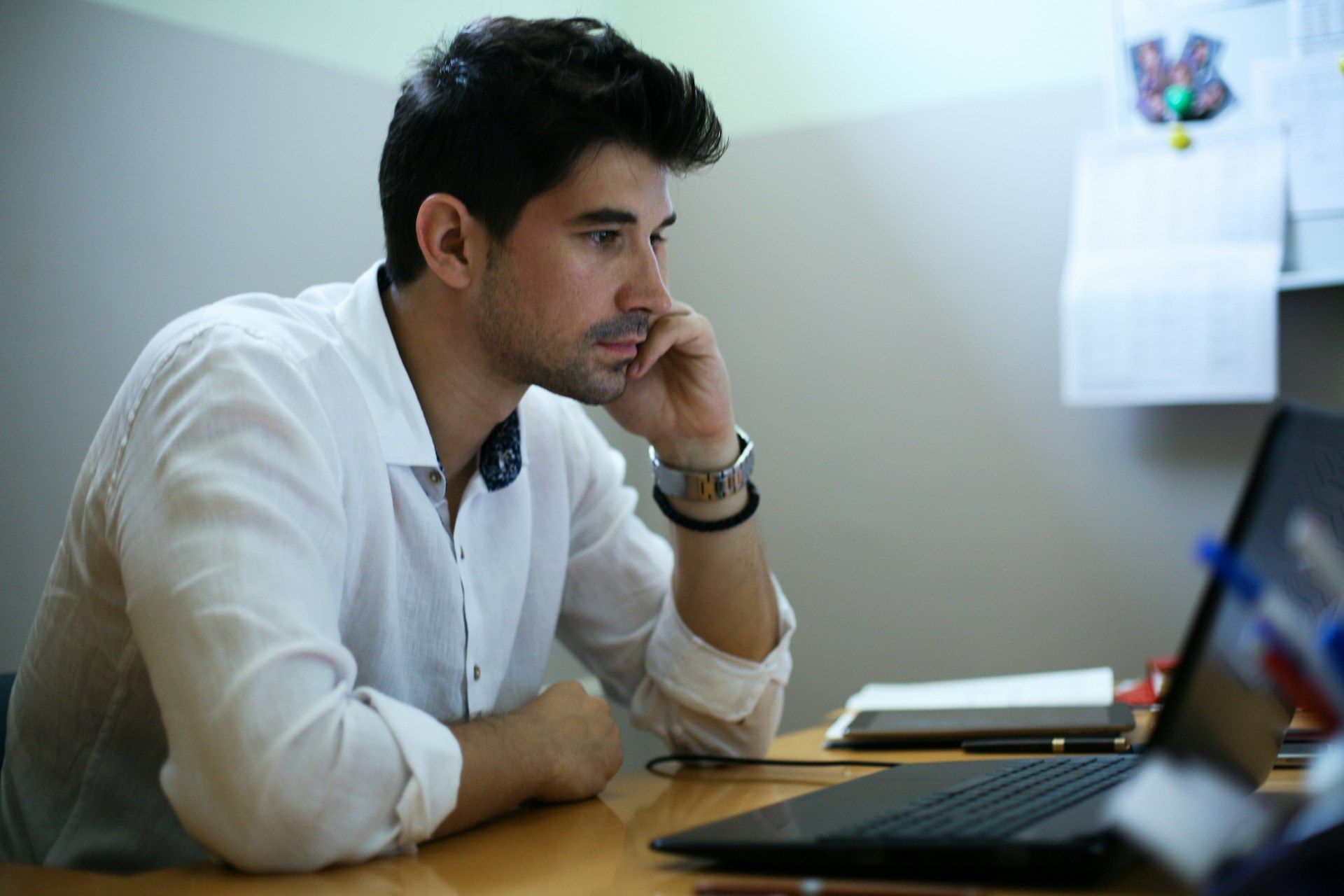 A man is sitting at a table using a calculator and a pen.