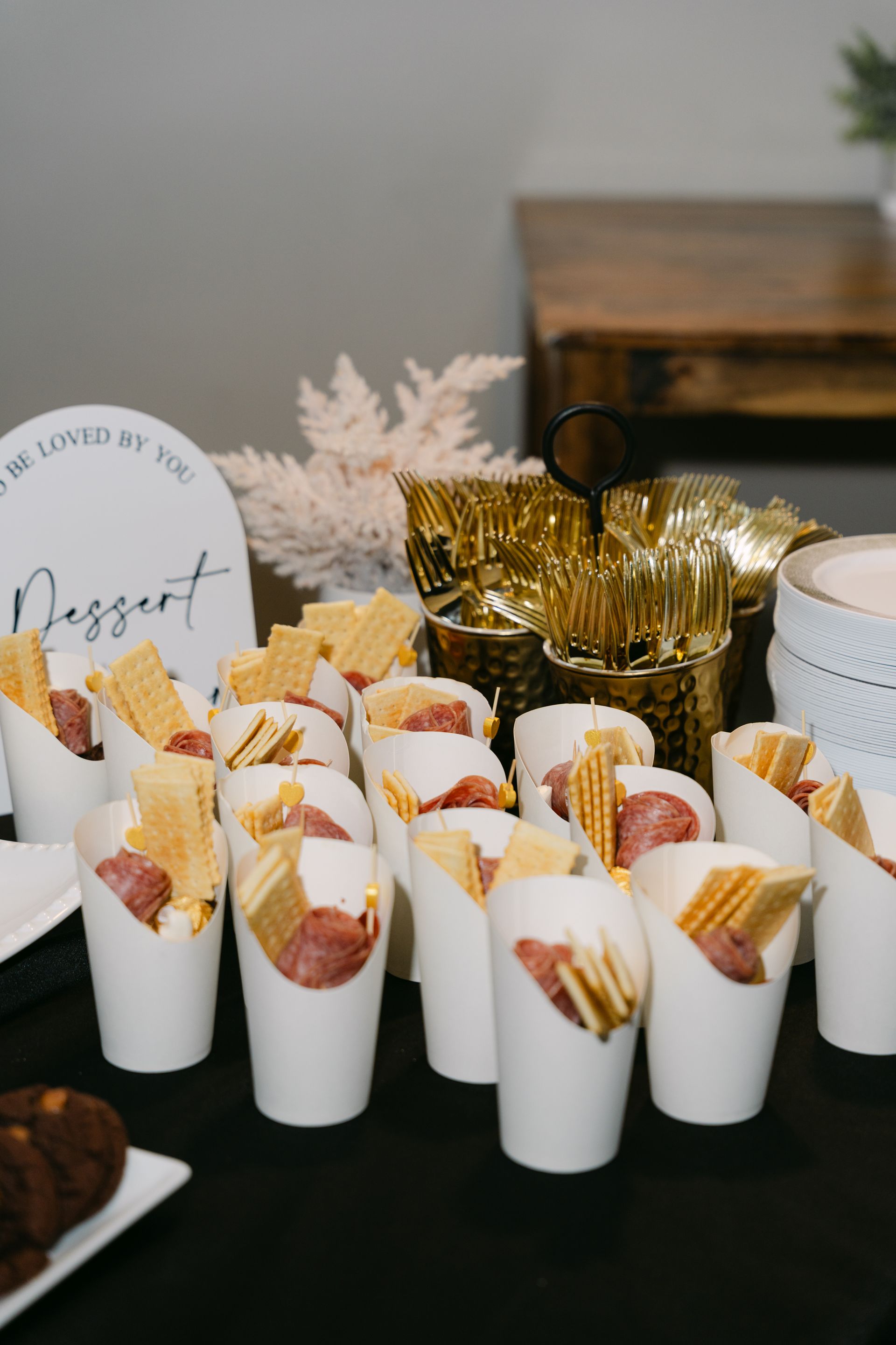 Dessert display: Cups holding sausages and crackers, with gold utensils and sign on a black table.
With Love, Wedding management, Milwaukee Wedding Coordinator