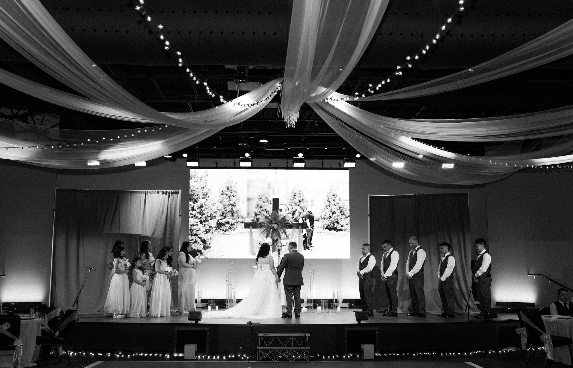 Wedding ceremony on stage with wedding party. Snowy forest backdrop, draping, and string lights.
With Love, Wedding management, Milwaukee Wedding Coordinator