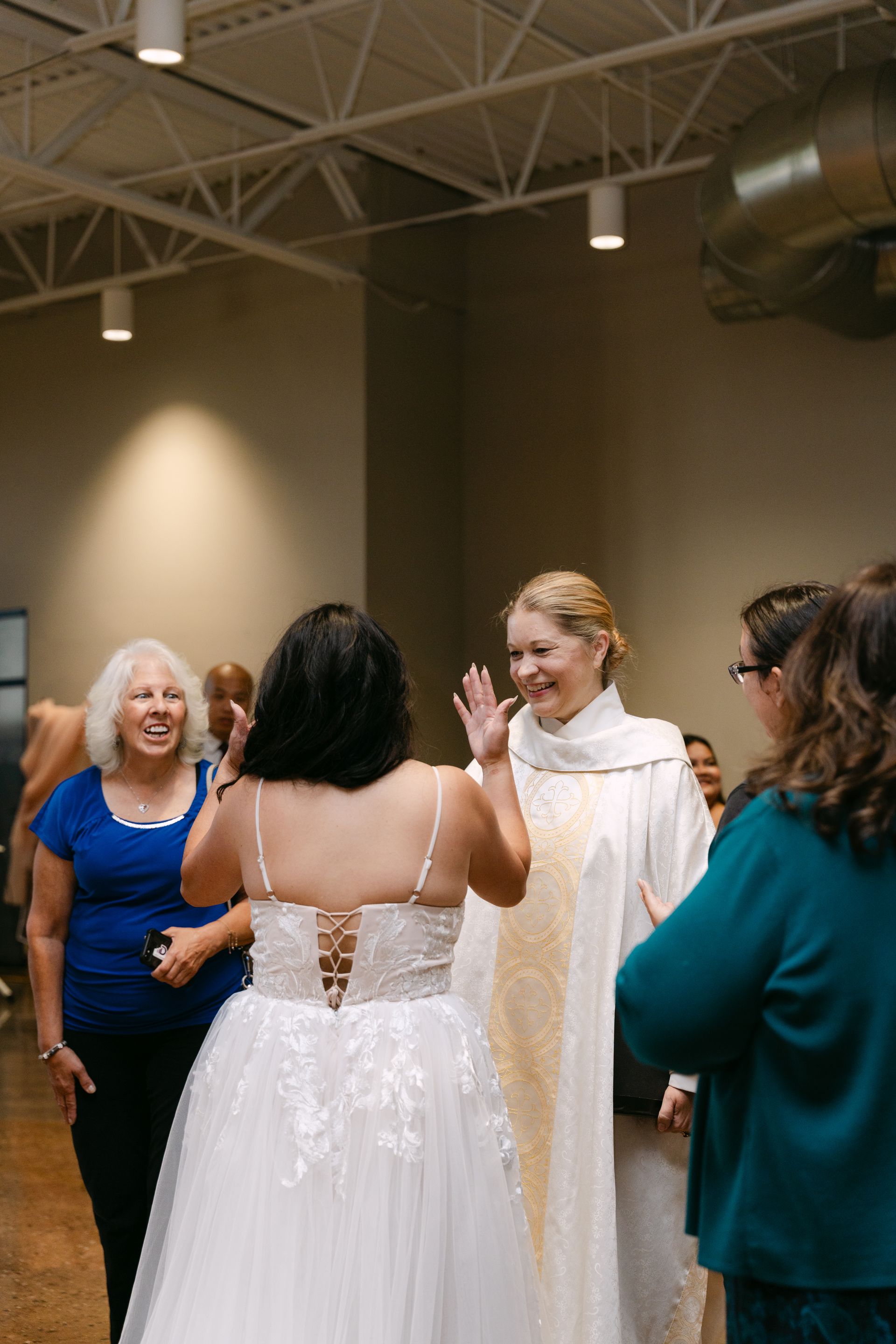 Bride in a white gown and priest in white robe with gold trim greeting guests at an event.
With Love, Wedding management, Milwaukee Wedding Coordinator