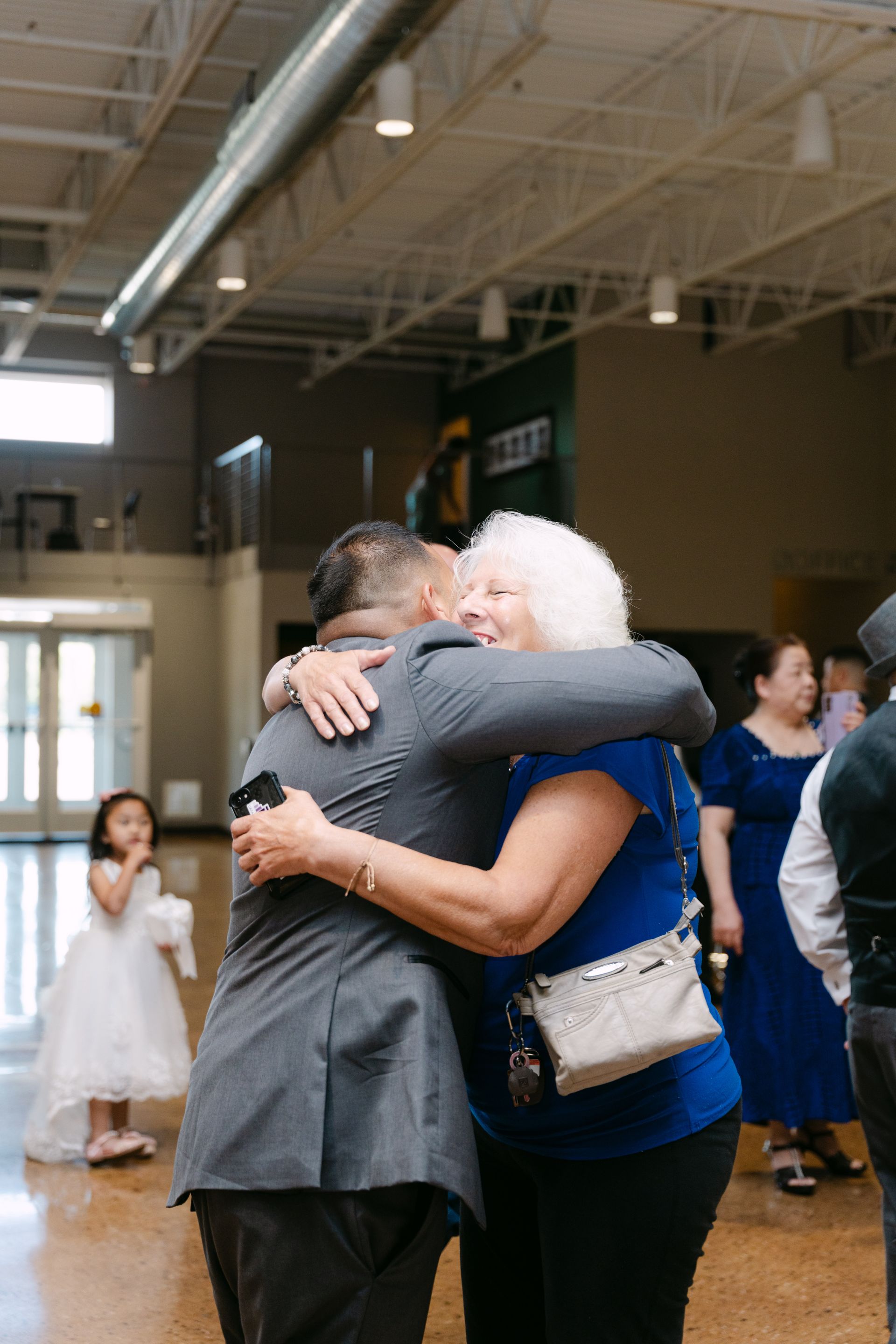 Man in gray suit hugs woman in blue shirt, light-filled room.
With Love, Wedding management, Milwaukee Wedding Coordinator
