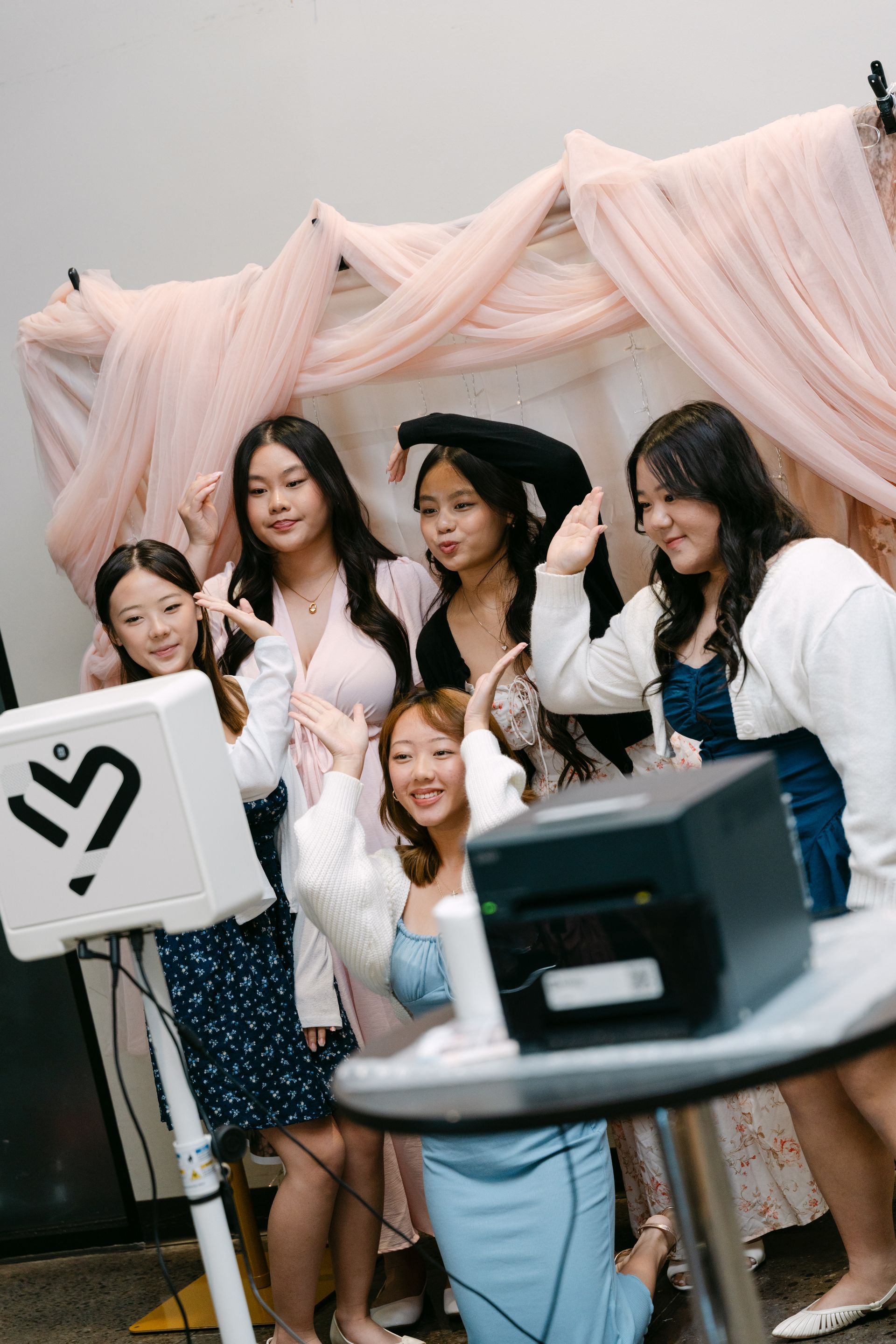 Five young girls pose at a photo booth with pink fabric backdrop. They smile and gesture, some in formal wear.
With Love, Wedding management, Milwaukee Wedding Coordinator