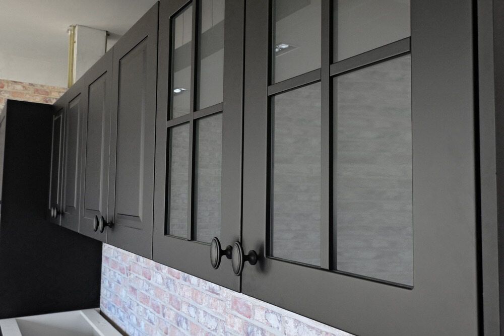 A Kitchen With Black Cabinets And Glass Doors — Meredith Kitchens In Moffat Beach, QLD