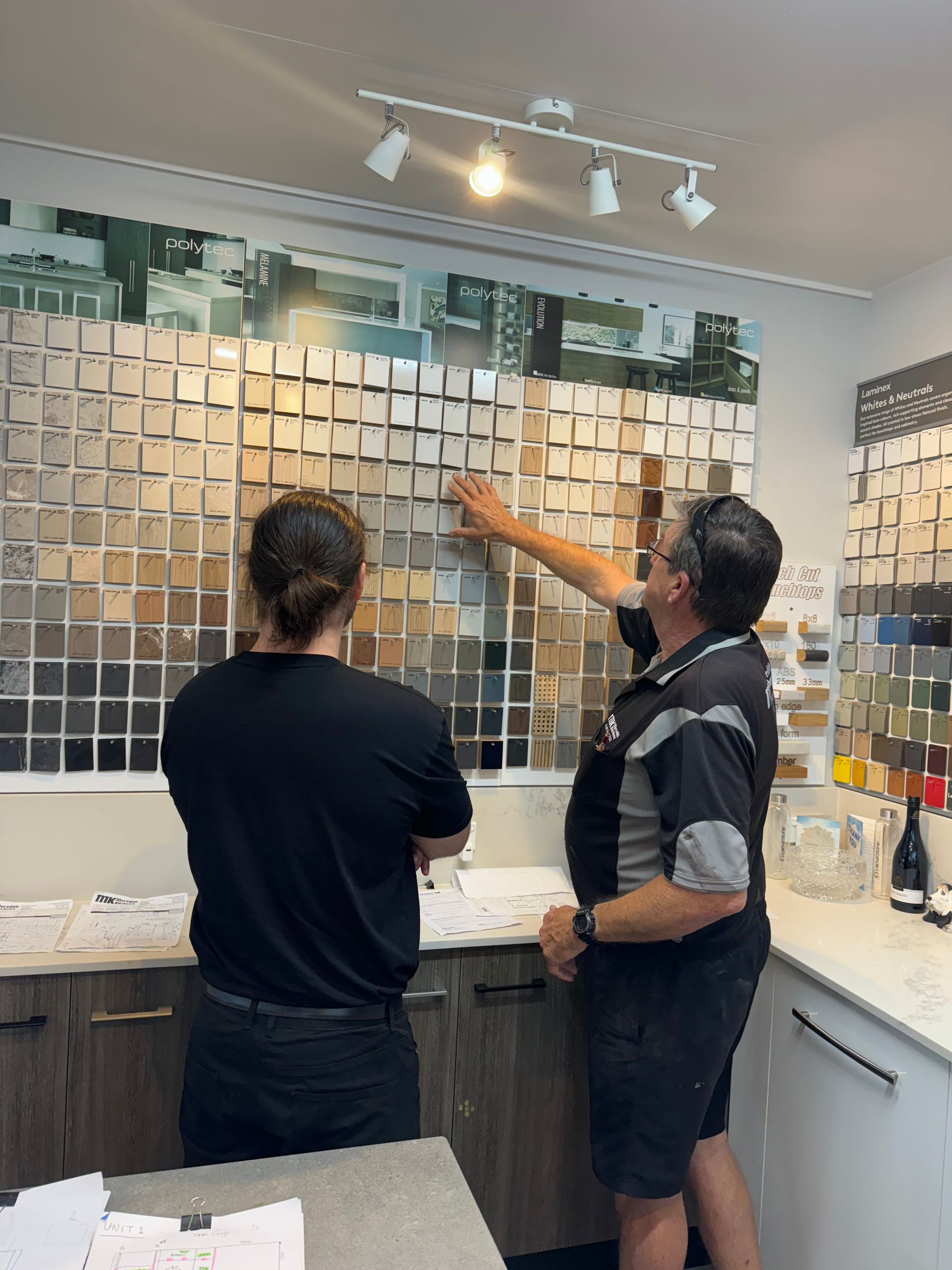 Two People Standing Looking At Colour Swatches In A Showroom  — Meredith Kitchens In Moffat Beach, QLD