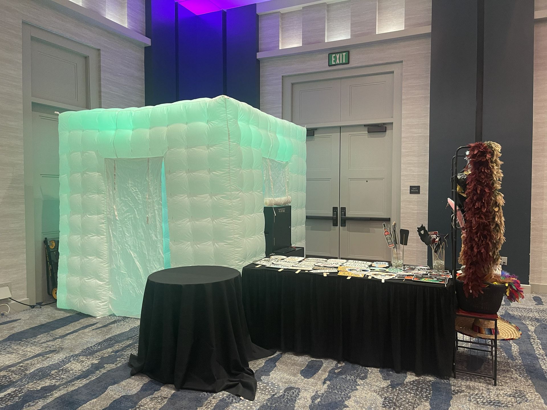 Glowing mint-green booth setup beside black-draped tables in a banquet hall