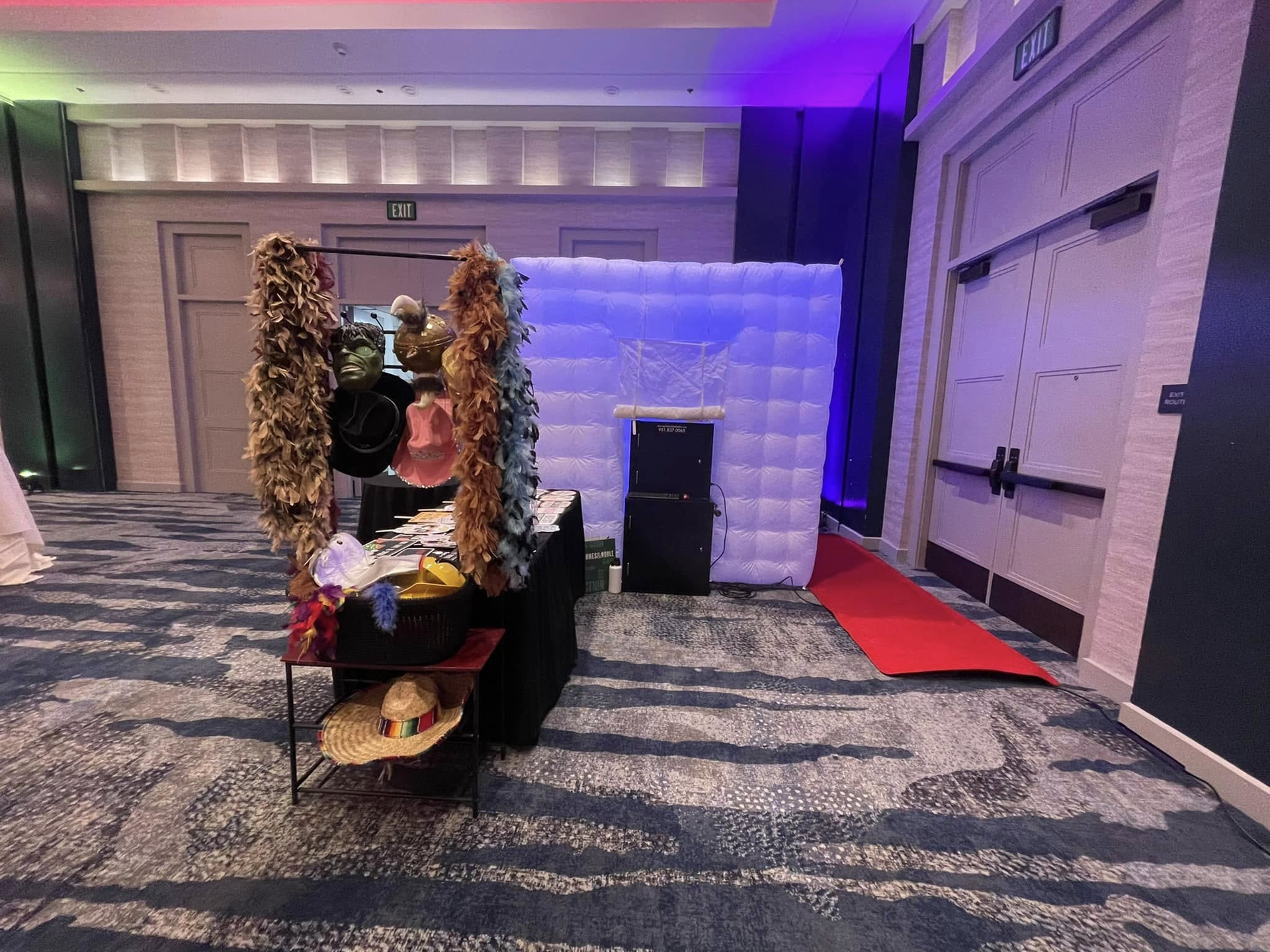 Decorated chair in a ballroom with floral garlands, white backdrop, and patterned carpet under purple lighting