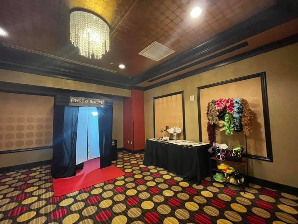 Hotel event entrance with red carpet, blue curtains, and a decorated table beside a floral display
