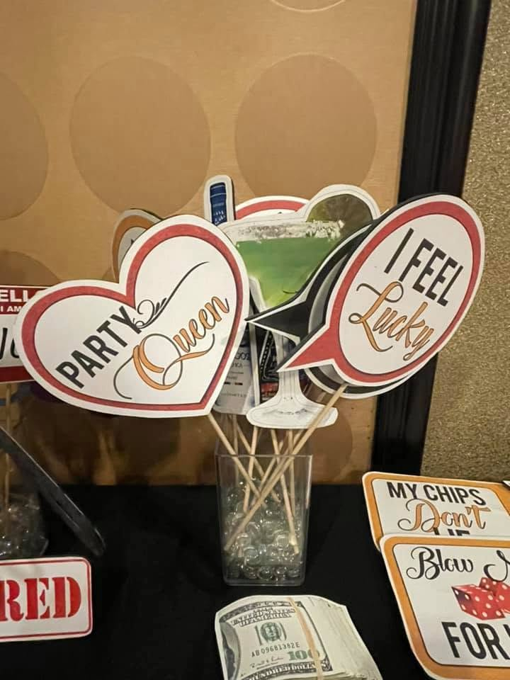 Decorative party signs in a vase, including “Party Queen” and “I Feel Lucky,” on a tabletop.