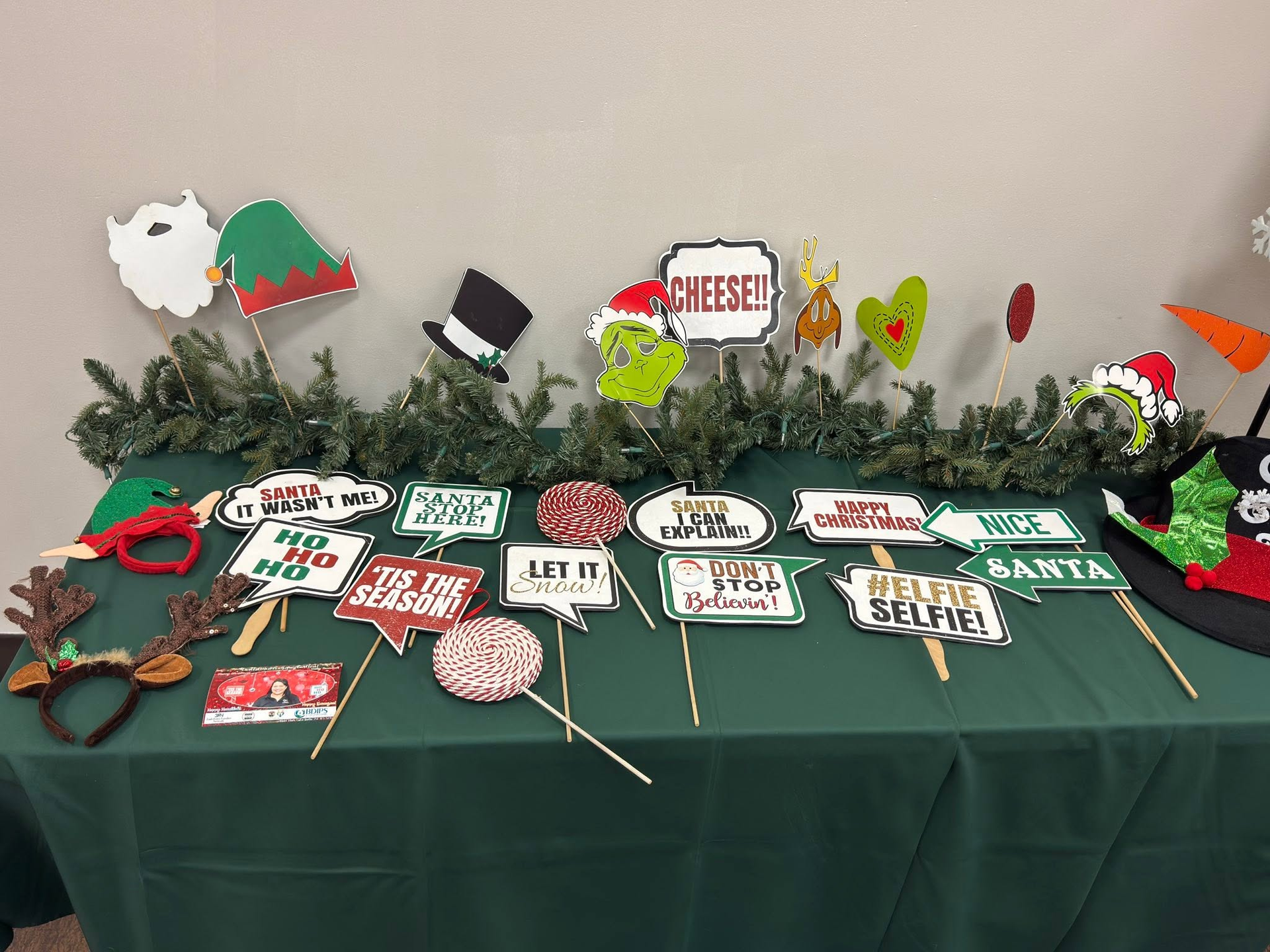 Green holiday craft display with small decorated signs, ornaments, and cheese-themed pieces on a table