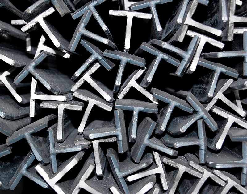 Una pila di pezzi di metallo a forma di T su uno sfondo nero