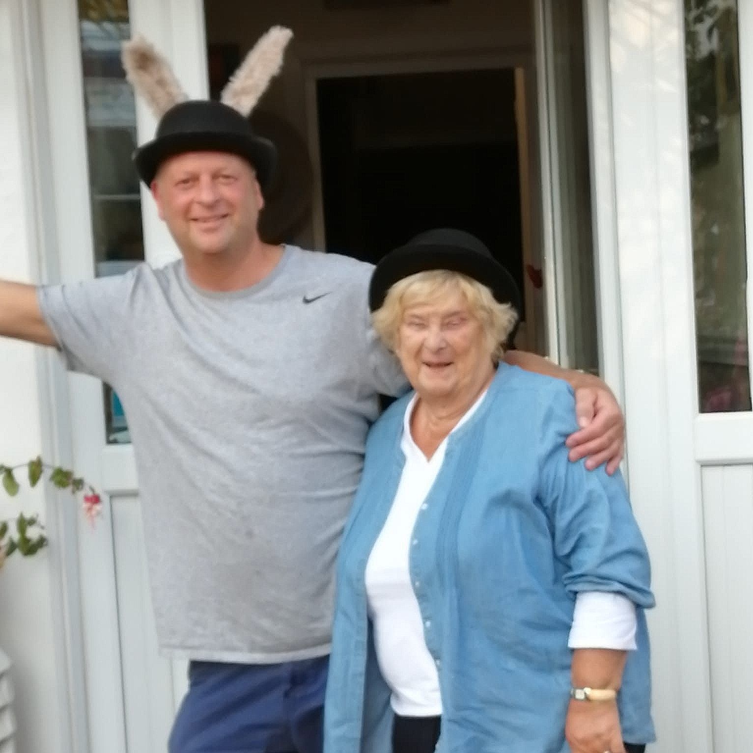 A man wearing bunny ears stands next to an older woman