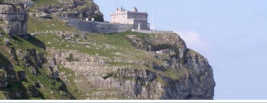 A castle is sitting on top of a rocky cliff.