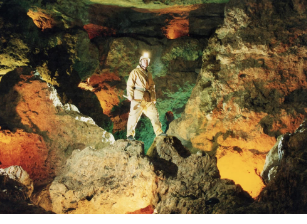 A man in a cave with a light on his head