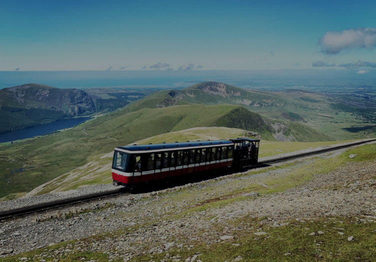 A train is going down the tracks on top of a mountain.
