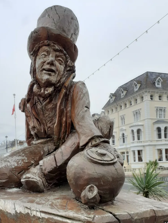 A statue of a man wearing a top hat and holding a pot