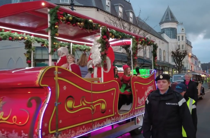 A police officer is standing next to a sleigh with santa claus on it.
