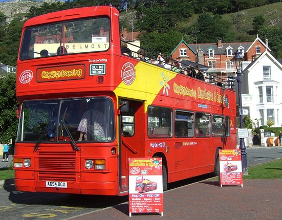 A red double decker bus is parked in a parking lot