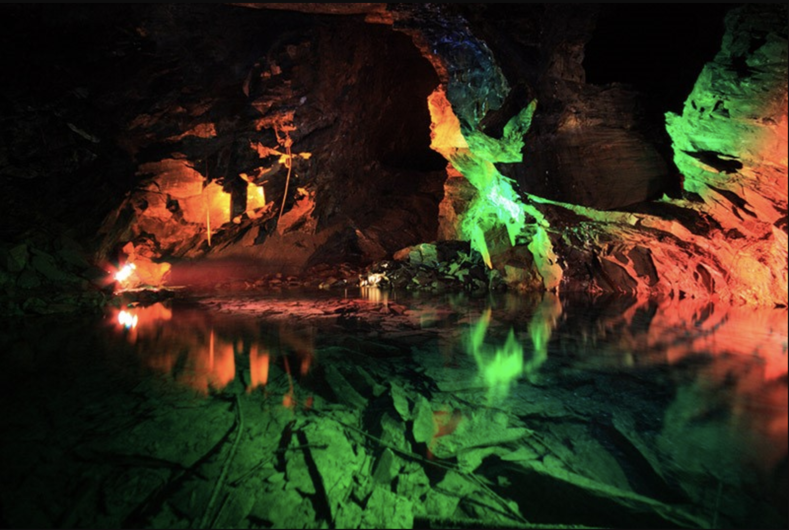 A dark cave with green and red lights on the walls