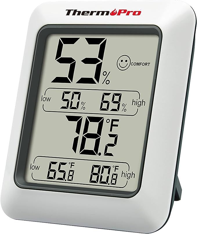 A digital thermometer and humidity meter with a smiley face on the screen.