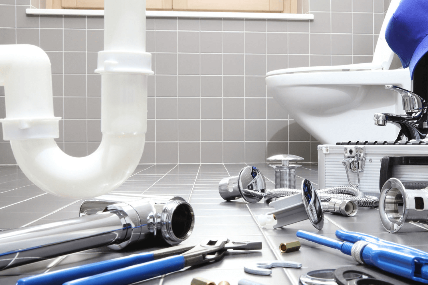 A plumber is fixing a toilet in a bathroom.