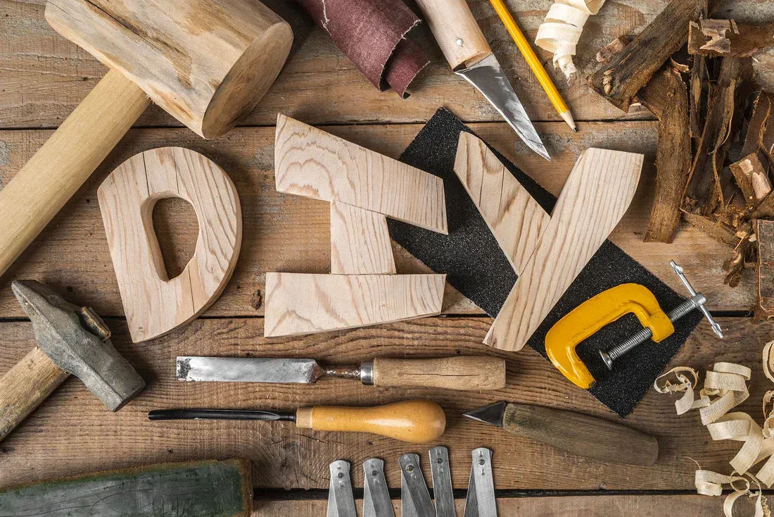 The word diy is made out of wood and surrounded by woodworking tools.