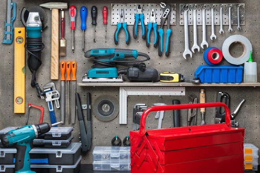 A wall filled with lots of tools and a toolbox.