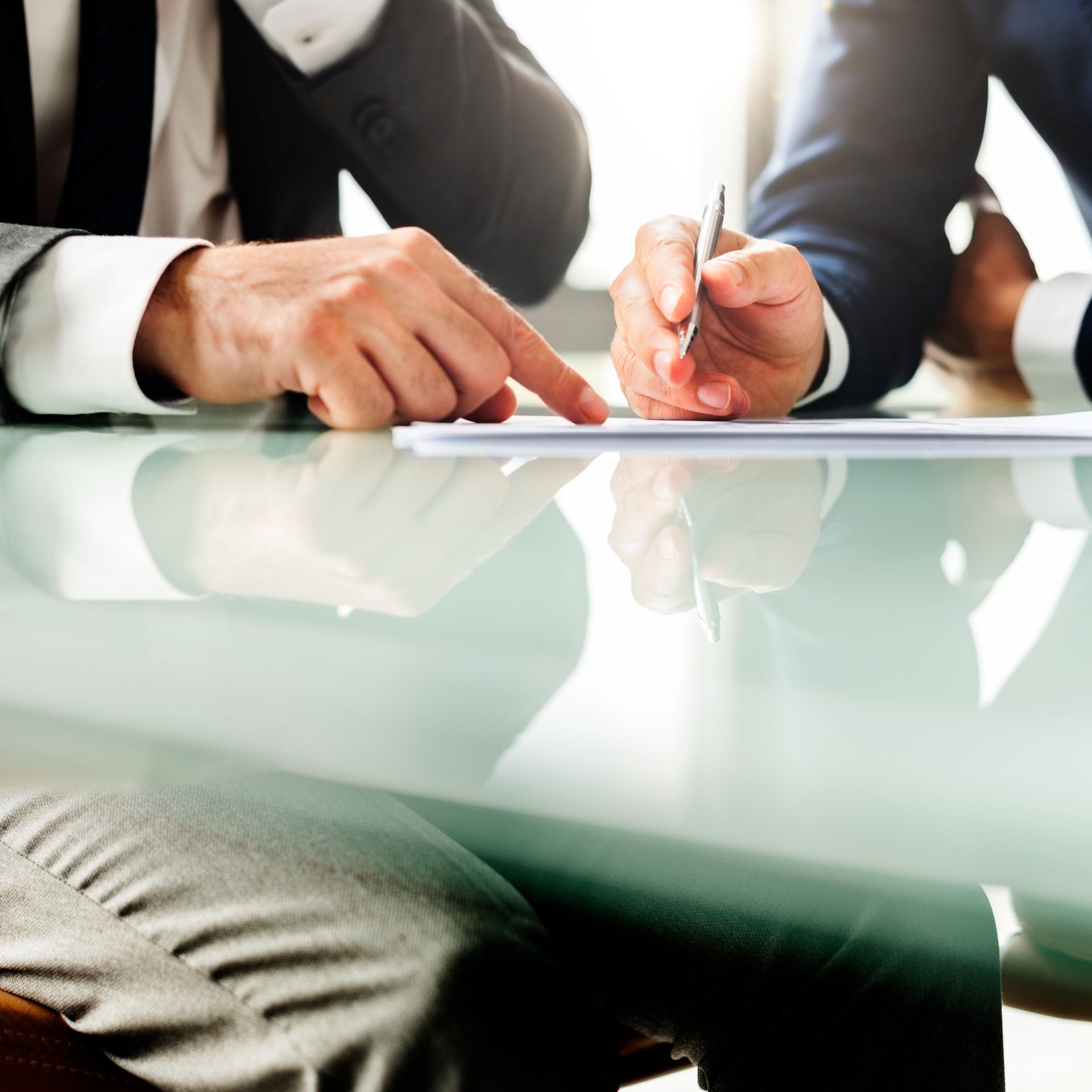 Two businesspeople in suits reviewing a document together at a table.
