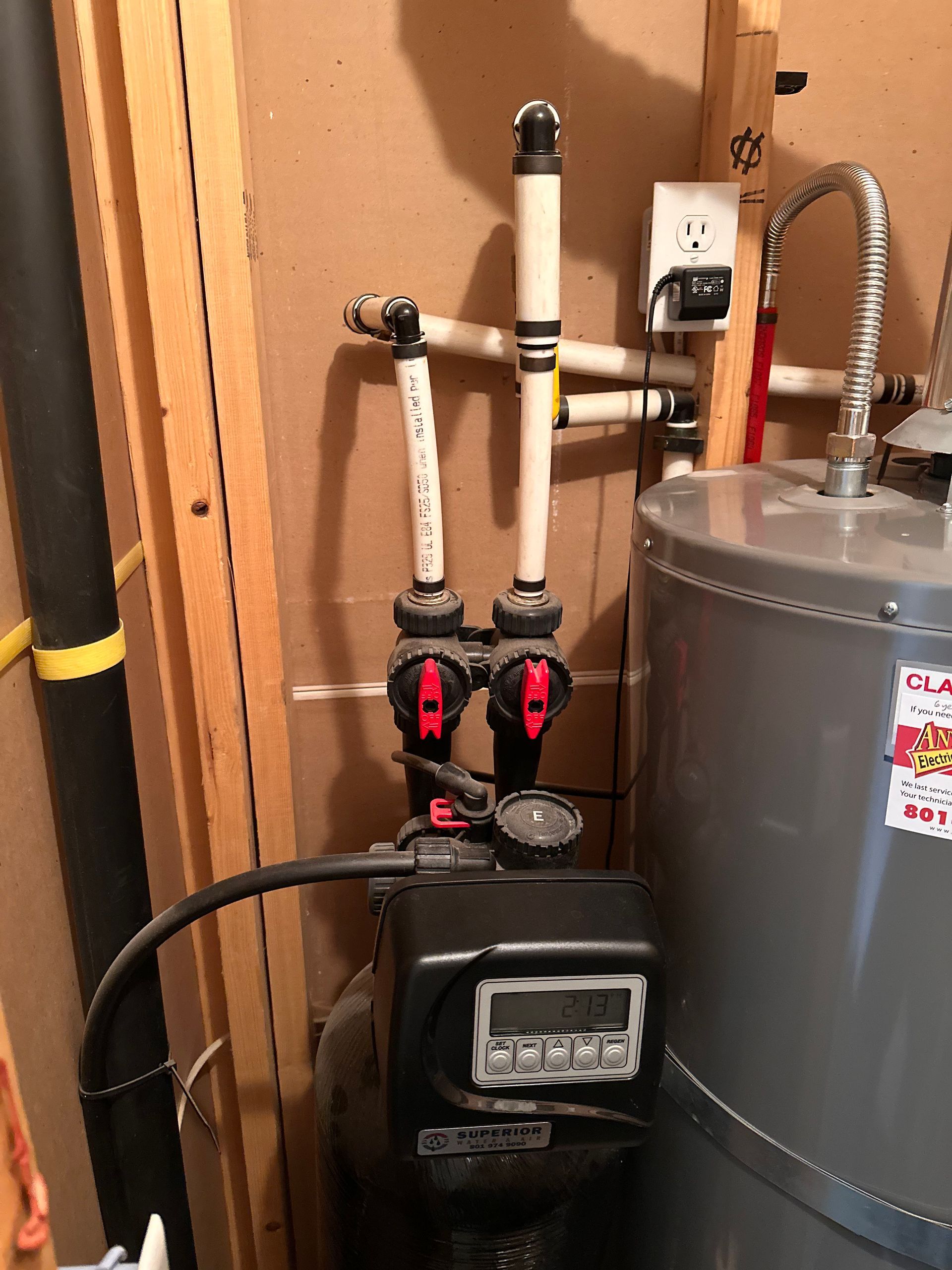 Water heater and furnace with exposed plumbing and pipes in a utility closet.