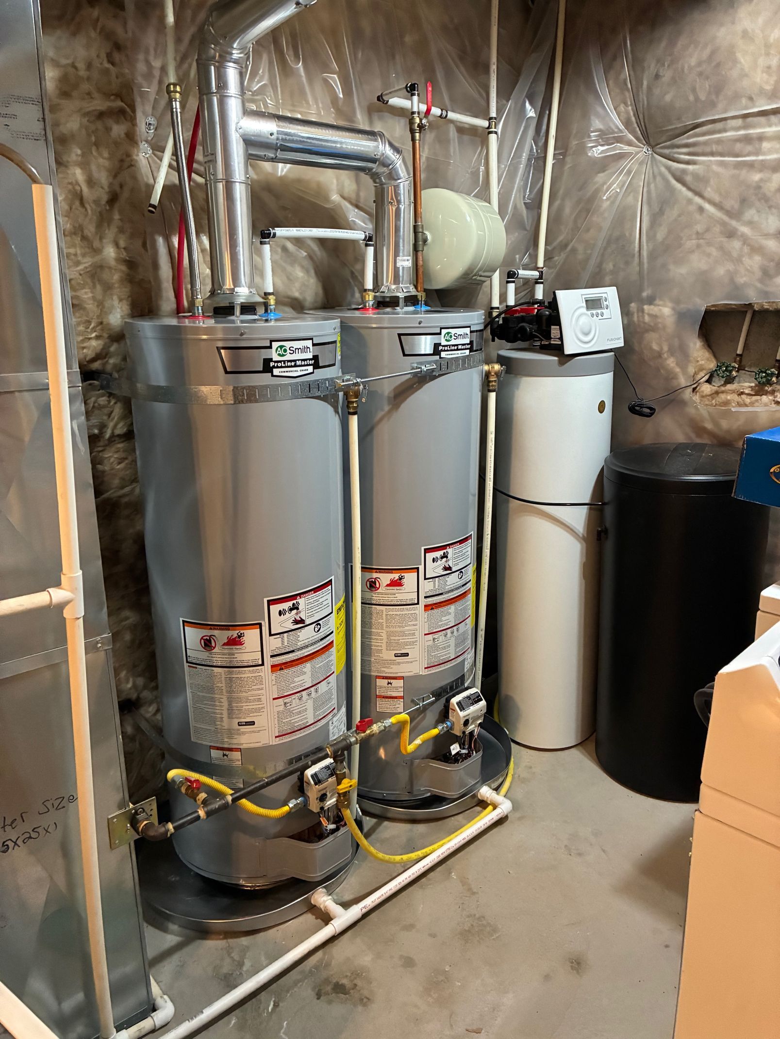 Two water heaters and a water softener in a basement utility room