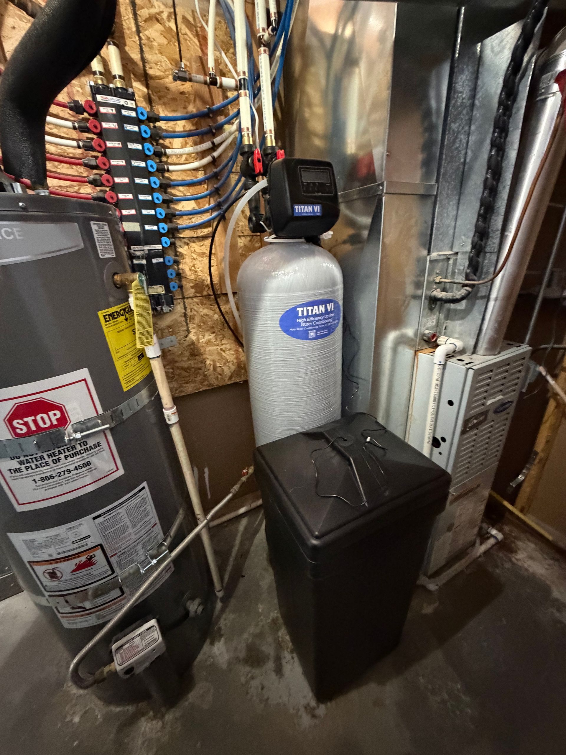 Basement utility area with water softener tanks, pipes, and HVAC equipment.